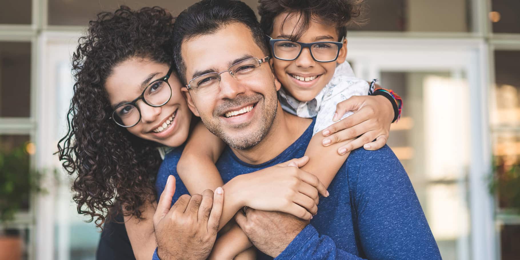 A middle-aged man carrying two children over his shoulders.