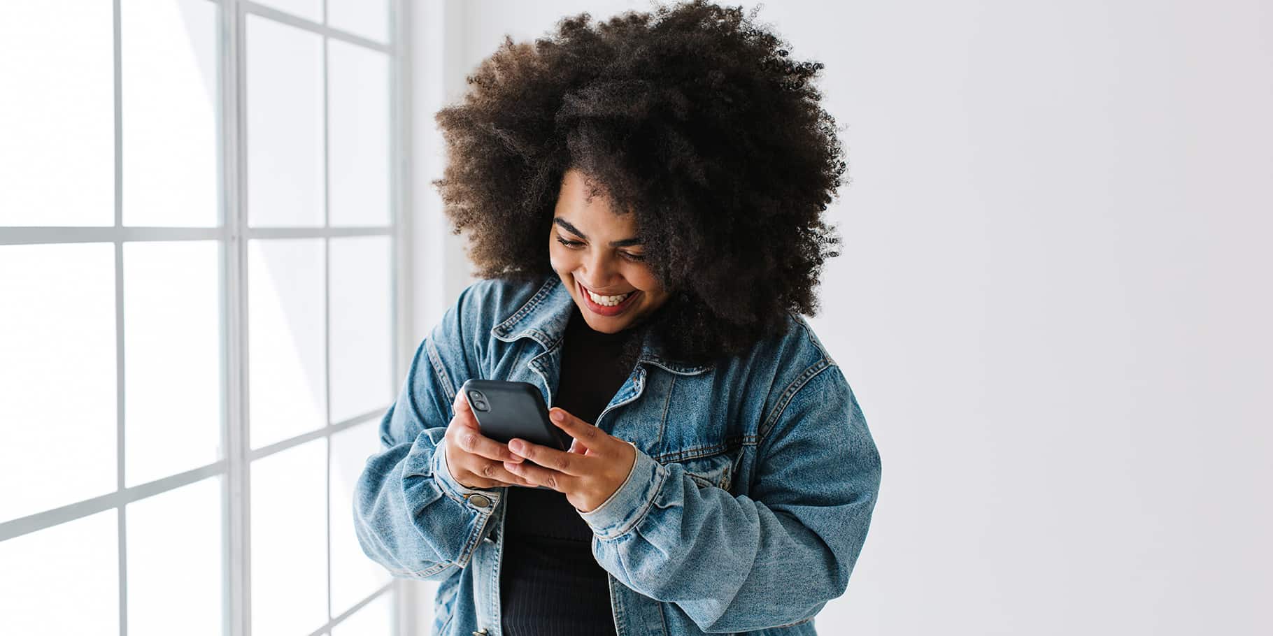 A smiling young woman holding a smartphone.